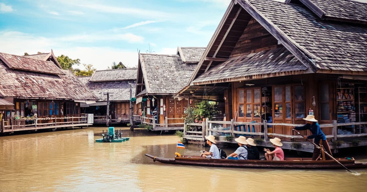 Tourists navigating a vibrant floating market by boat, a classic inclusion in thailand holiday packages.