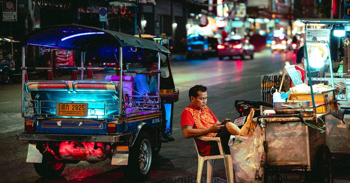 Colourful tuk-tuk and street food vendor illuminated at night in Thailand during the cheapest travel season