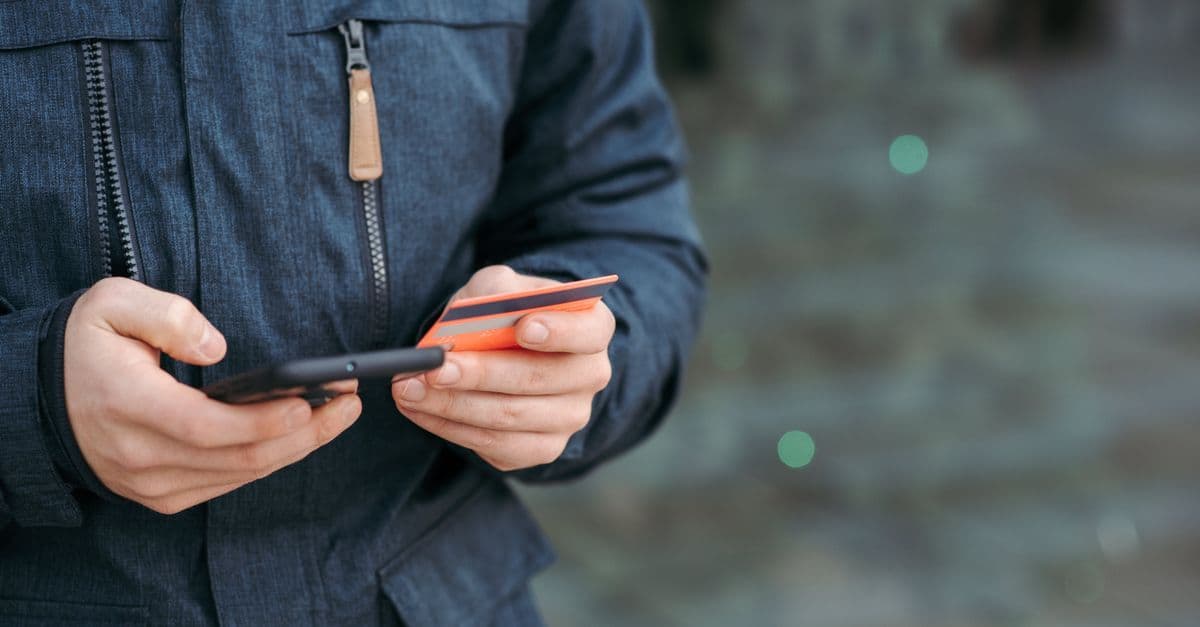 街中でスマートフォンに決済情報を入力する男性、ドコモ回線なしでもdアカウントの確認と利用が可能