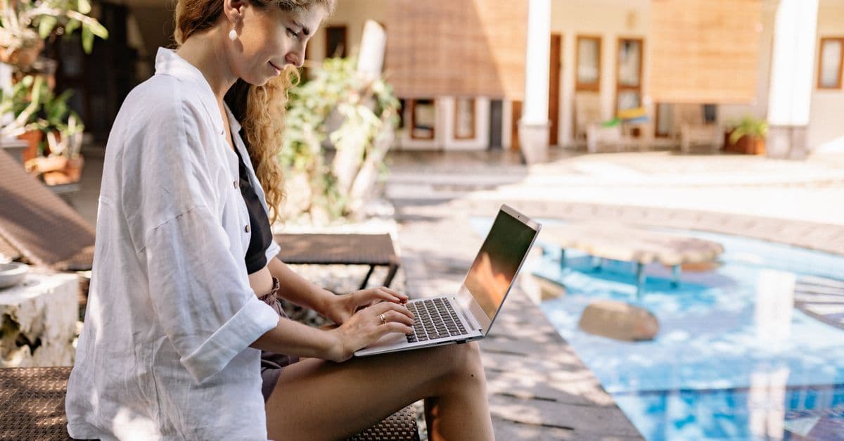 Remote worker using a laptop poolside at a Bali resort, eligible under the Digital travel eSIM Bali visa E33B.