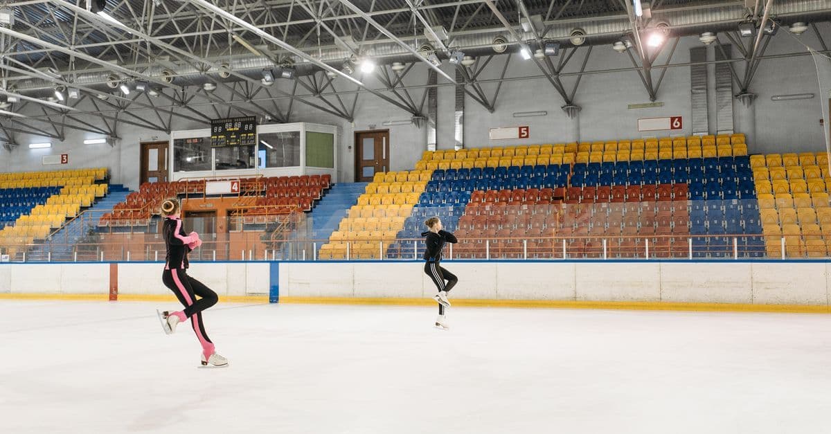 실내 아이스링크에서 점프를 연습하는 두 스케이터, 2026 년 동계 올림픽 여자 싱글 스케이팅 프리 스케이팅 채점 방식을 보여줍니다.