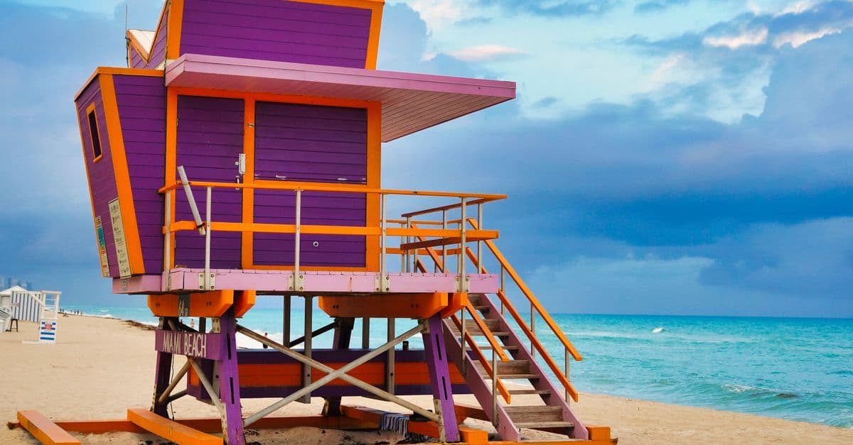 Una torretta di salvataggio viola e arancione si affaccia sulla spiaggia e sul mare turchese di Miami.
