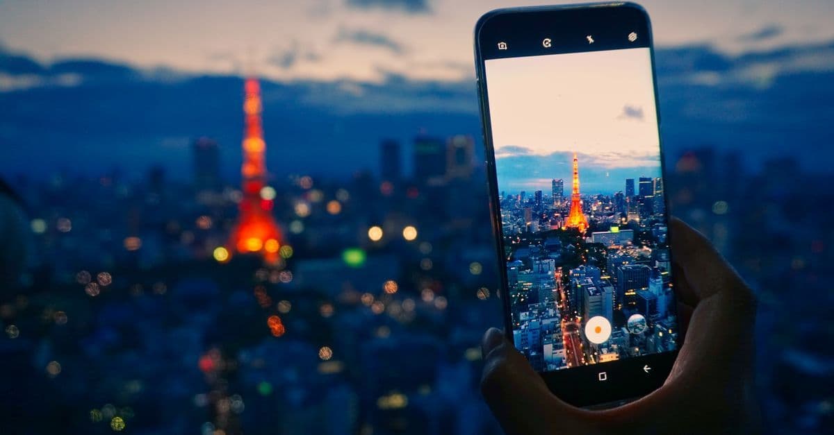 Tokyo Tower glowing at night captured through a smartphone screen, ideal for connected travelers