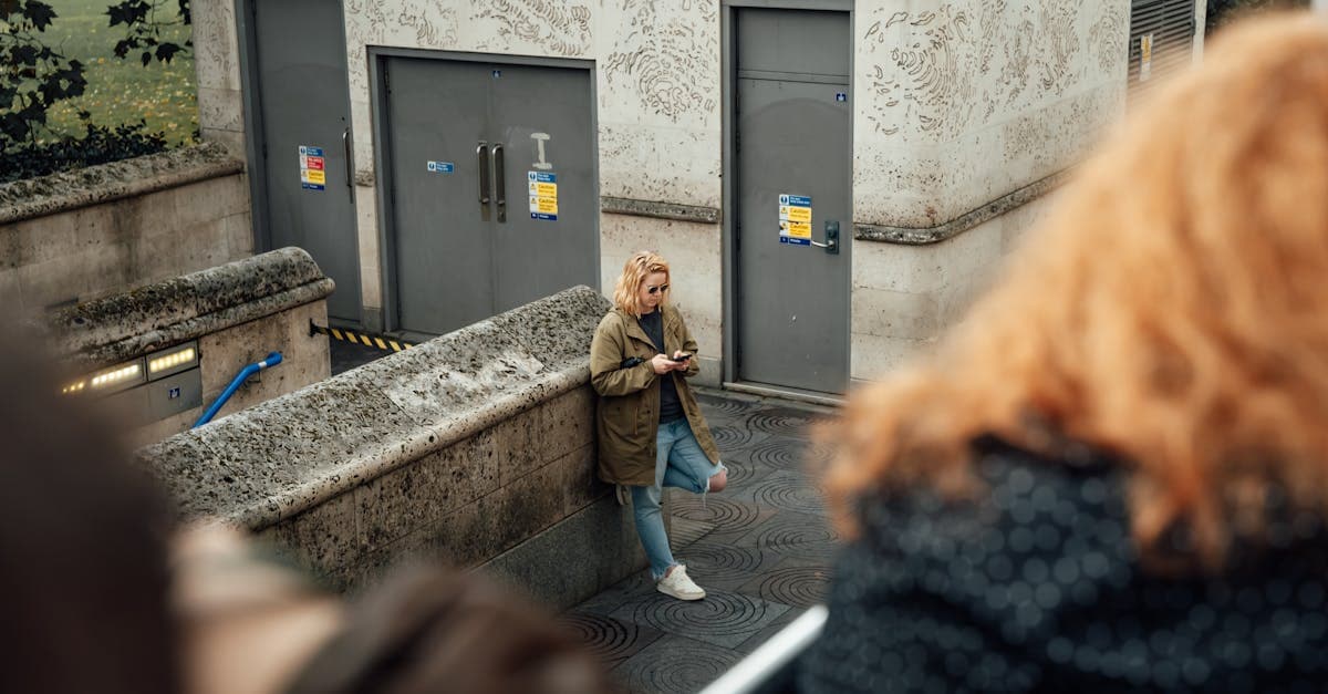 Woman using her phone near a stone wall in London, staying connected while exploring the city.