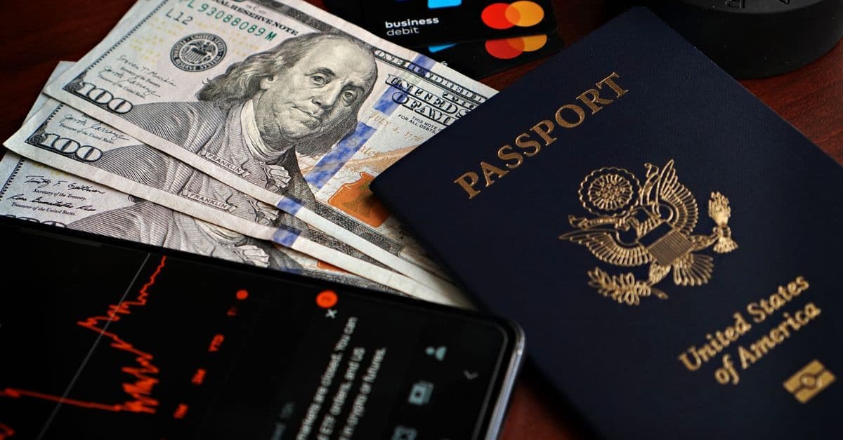 Passport, banknotes, credit cards, and smartphone displaying financial data needed for a US visa appointment.