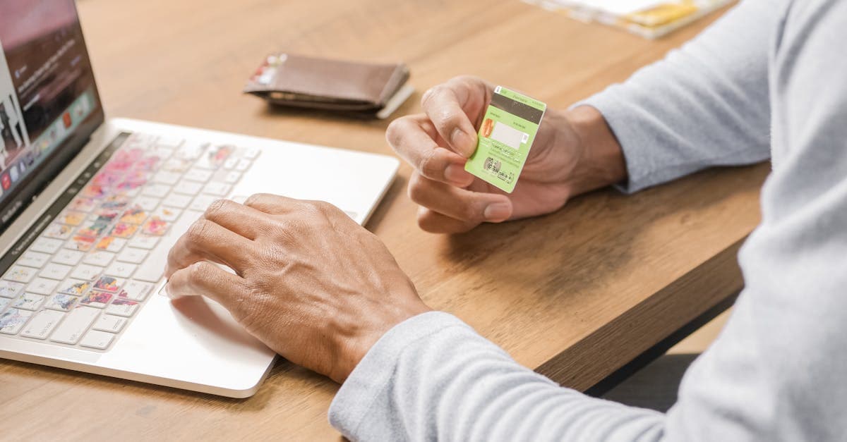 Osoba trzymająca kartę kredytową przy laptopie, kupująca turystyczną kartę eSIM na internet za granicą.