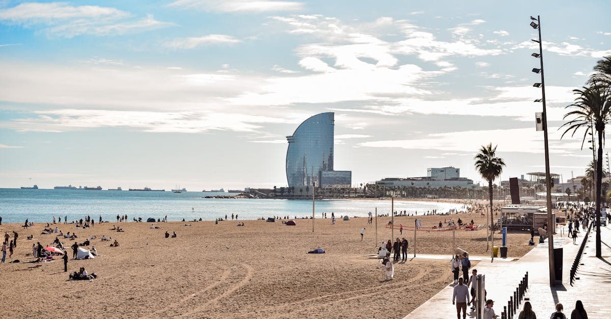Tłum turystów na plaży Barceloneta z widokiem na hotel W — symbol gorącego lata w Barcelonie.