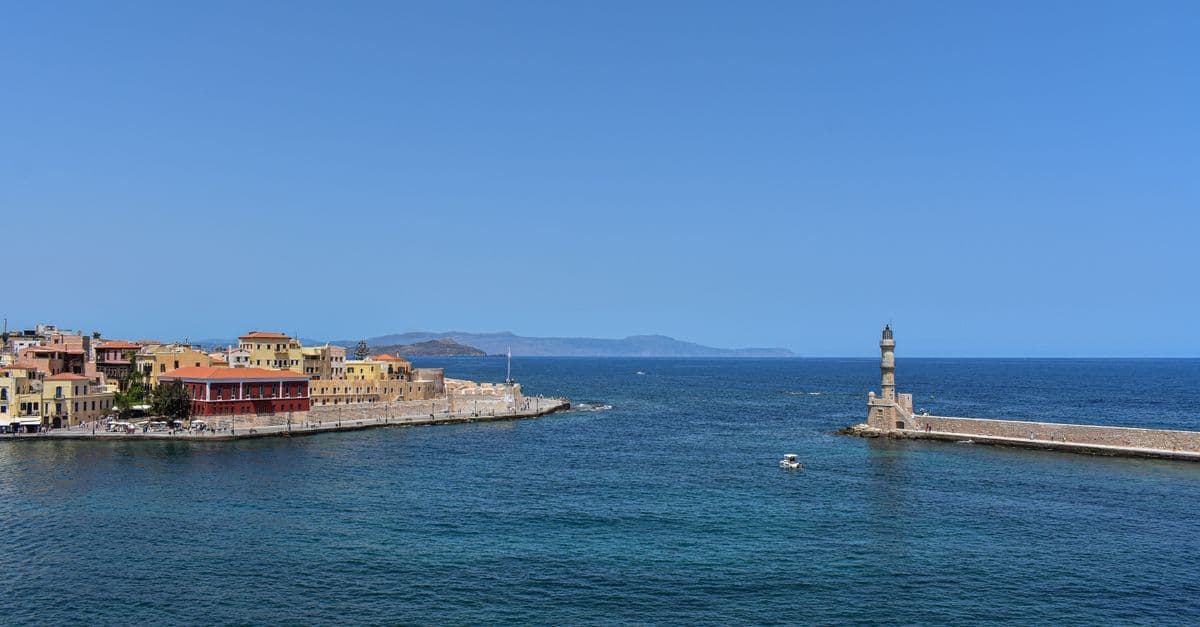 Blick auf den venezianischen Hafen von Chania mit Leuchtturm und bunten Häusern am Meer.