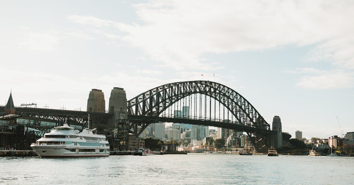 Cruise ship passing beneath Sydney Harbour Bridge on a sunny day, departing on a cruise to New Zealand from Sydney.