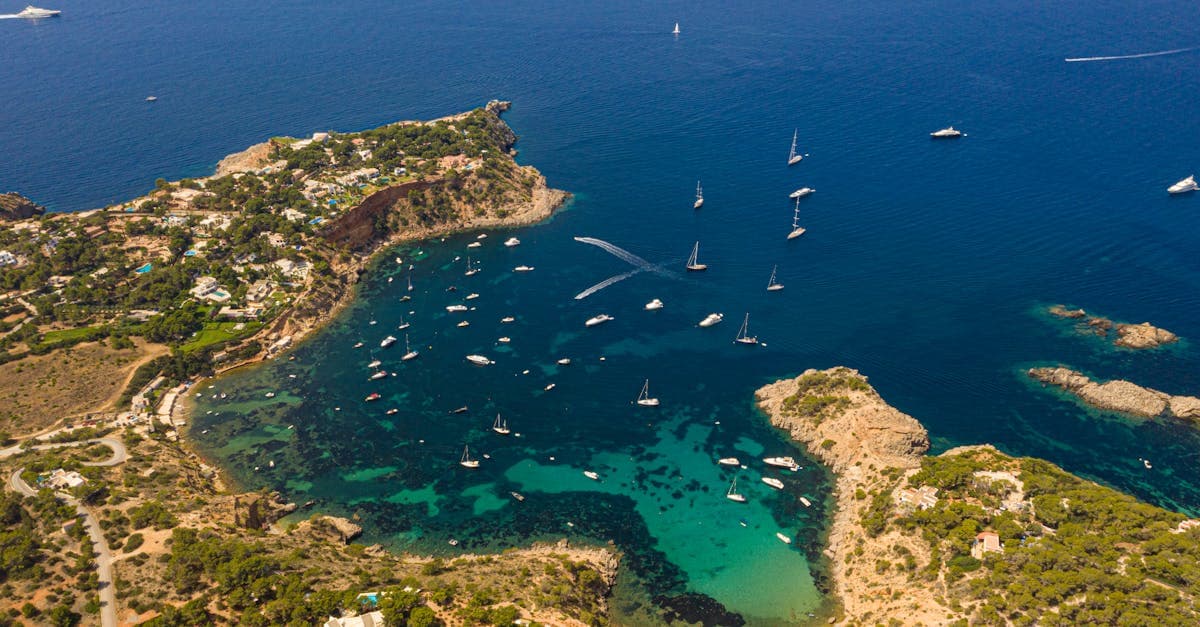 Aerial panorama of Ibiza's turquoise coves and anchored yachts, best reached by booking cheap flights to Ibiza