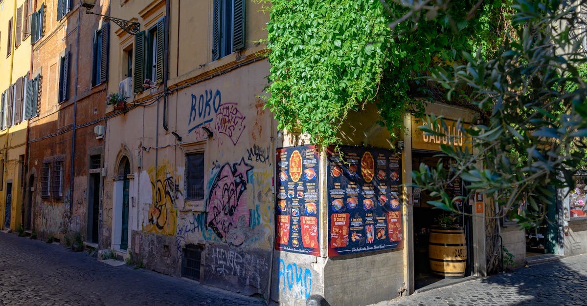 Calle empedrada de Roma con grafiti colorido y entrada de cafetería, escenario habitual donde comer a distintos precios reales.