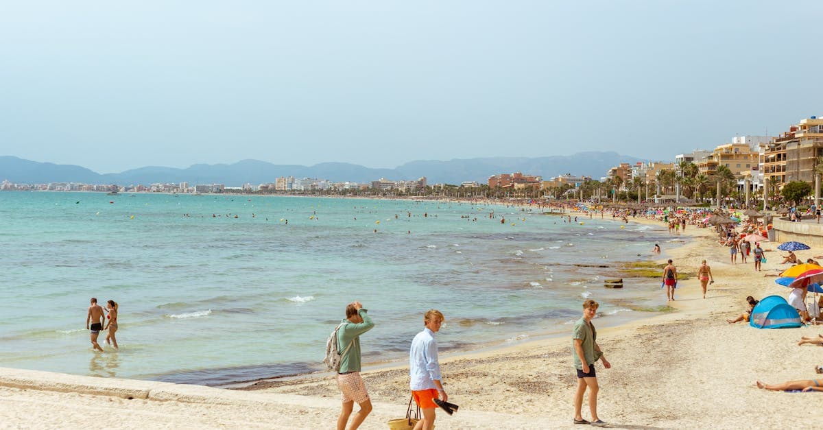 Belebter Strand an der Playa de Palma mit Sonnenbadenden und türkisblauem Mittelmeer im Sommer