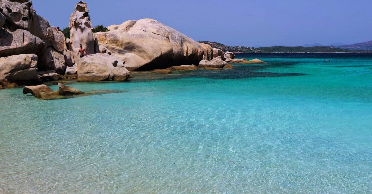 Atemberaubender Sandstrand mit kristallklarem türkisem Wasser und markanten Felsformationen beim Sardinien Urlaub