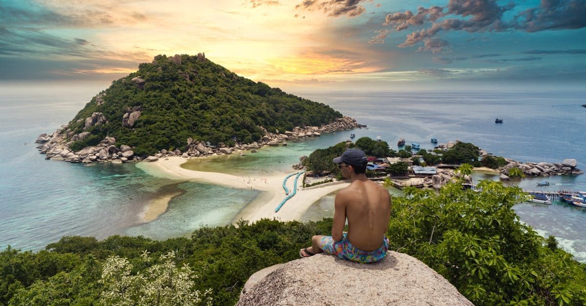 Traveller watching the sunset from a cliffside viewpoint over Koh Nang Yuan island in southern Thailand