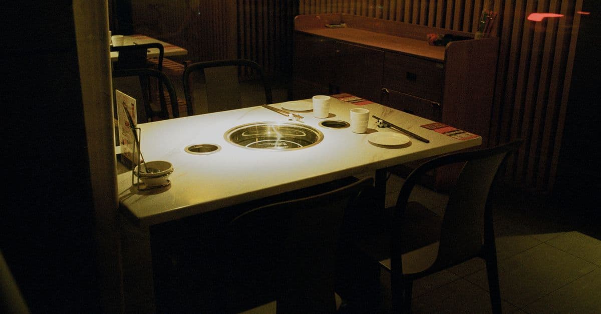 溫馨昏黃燈光下的獨食燒肉 yakiniku solo 餐廳,個人烤台整齊擺設靜候顧客入座