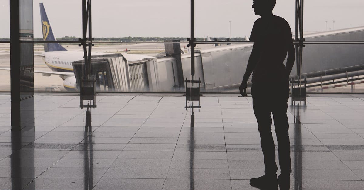 Silhouette of a man at El Prat airport with airplane reflections on glass walls.