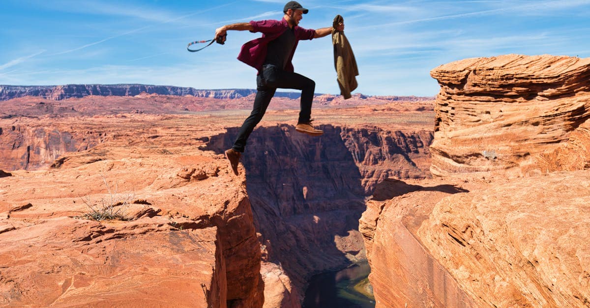 Man leaping across a dramatic red rock canyon in the USA, highlighting adventure cover in travel insurance policies