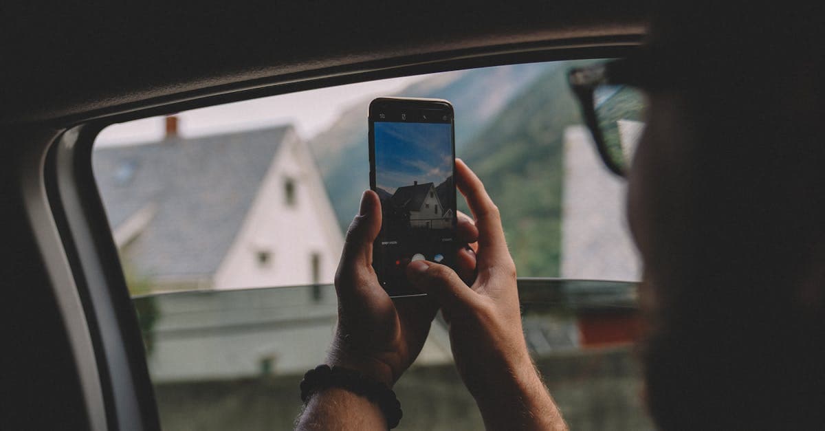Osoba fotografuje widok smartfonem przez okno samochodu podczas podróży zagranicznej bez roamingu
