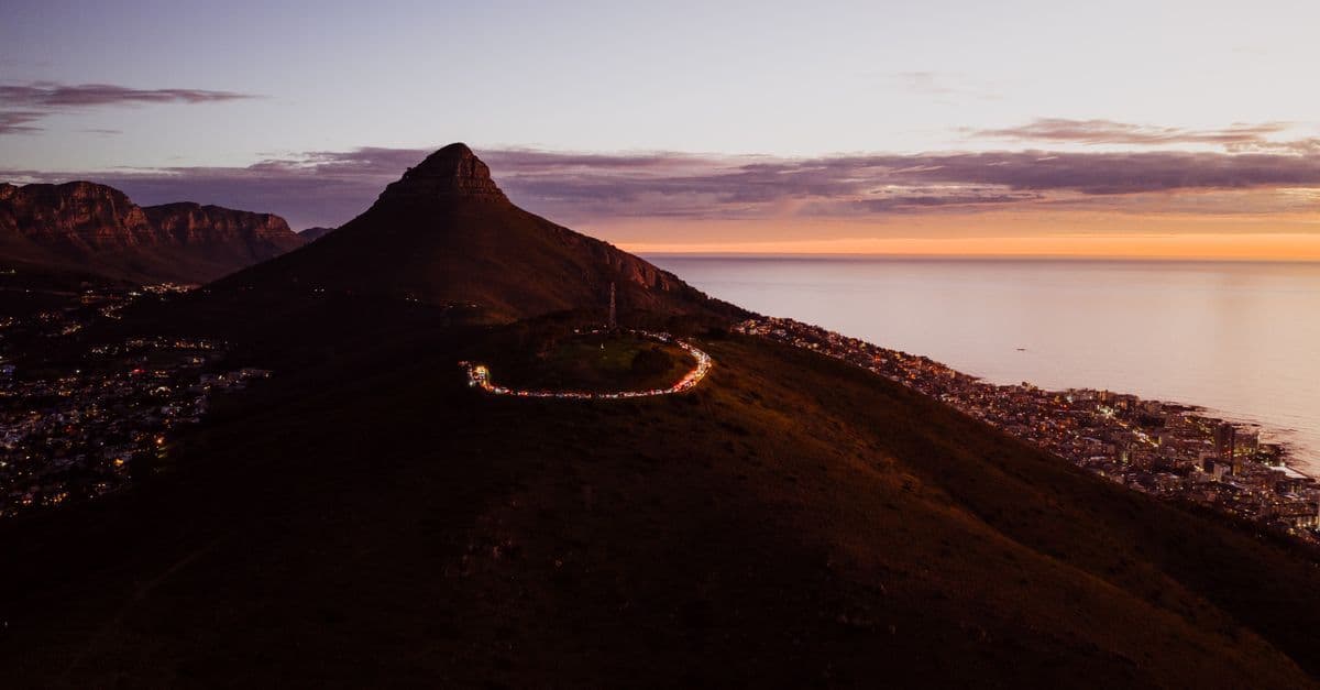 Sunset lights up the winding road around Signal Hill above Cape Town and the coastline.
