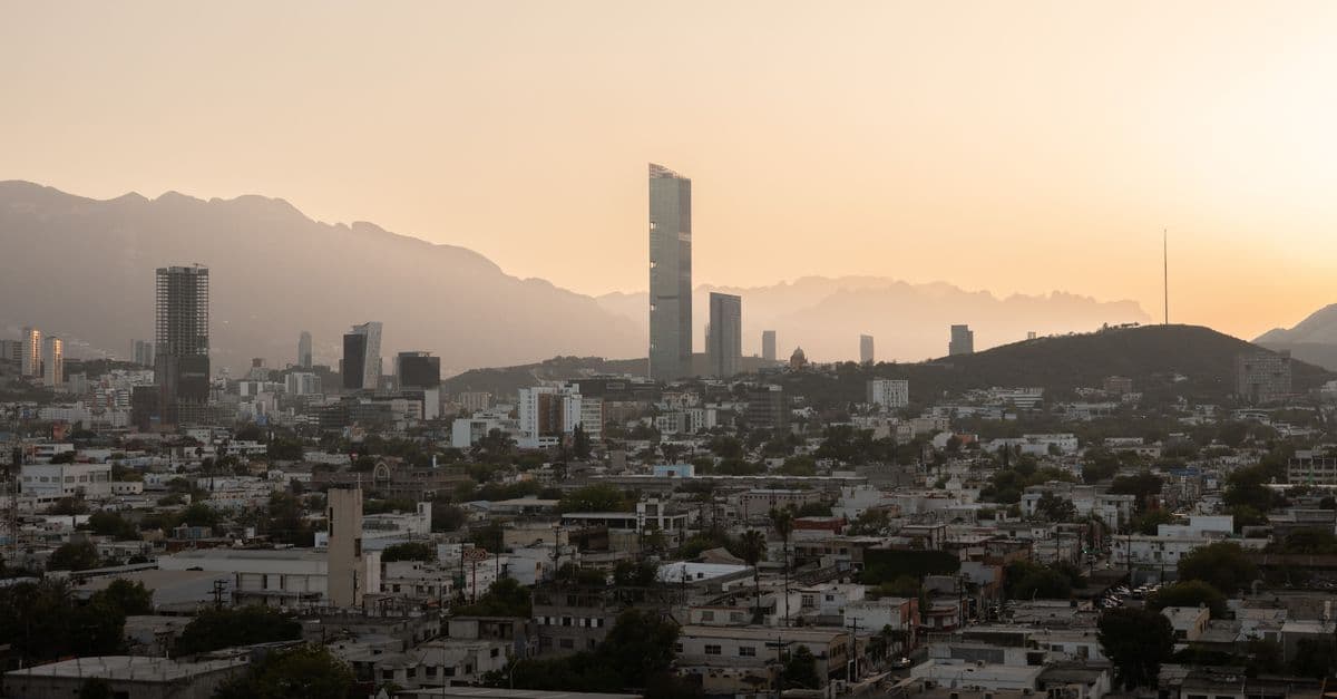 Sunset skyline of Monterrey Mexico featuring gleaming skyscrapers framed by the Sierra Madre mountain range.
