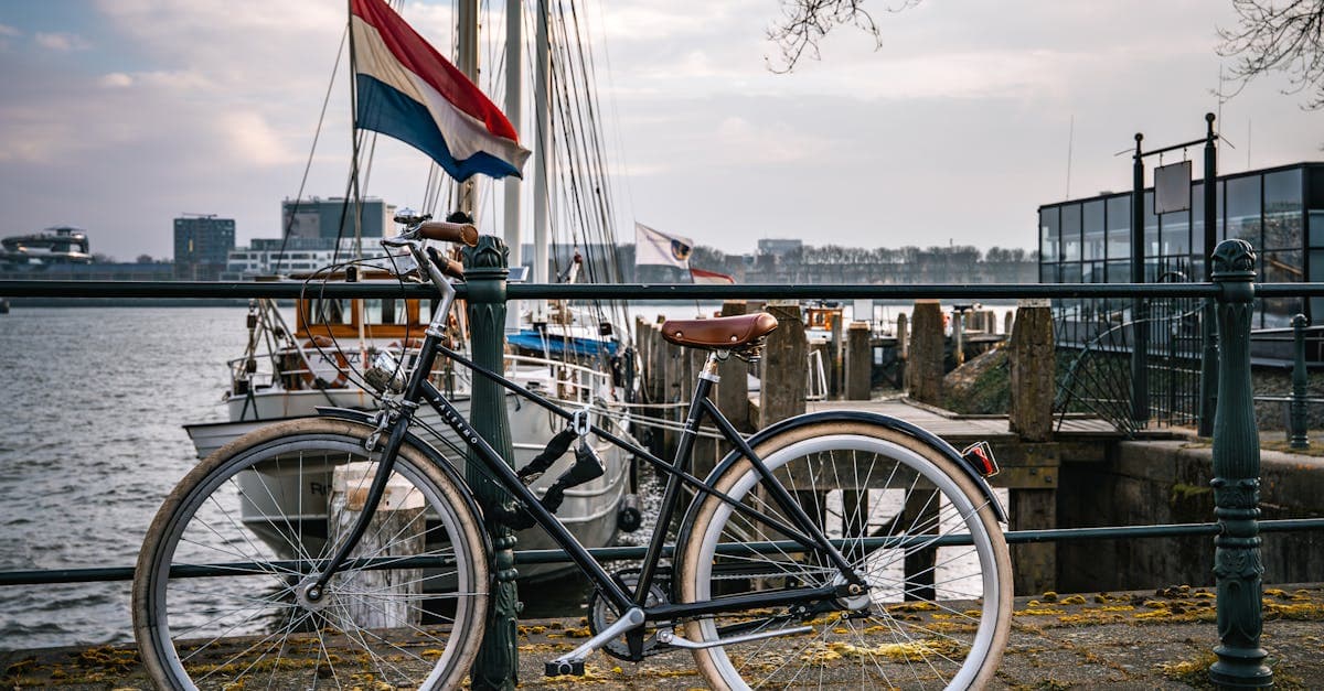 Fiets geparkeerd bij een Nederlandse haven met boten en de vlag, typisch beeld voor prepaid simkaartgebruikers