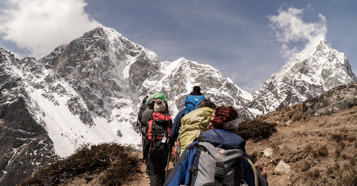 Group of trekkers hiking with snow-capped mountains behind them, an activity often excluded from standard travel insurance.