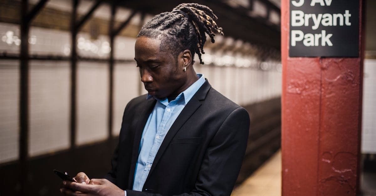 Young professional checking t mobile cell phone plans on his smartphone while waiting at a New York subway station.