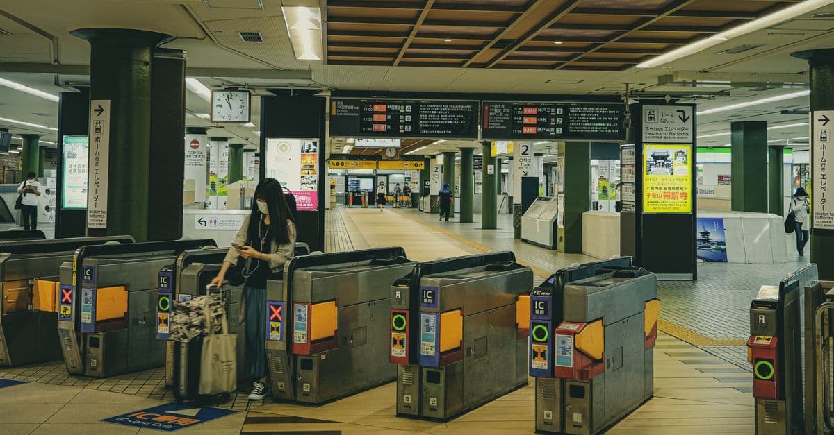 A traveler with a suitcase passes through ticket gates at a Tokyo train station.