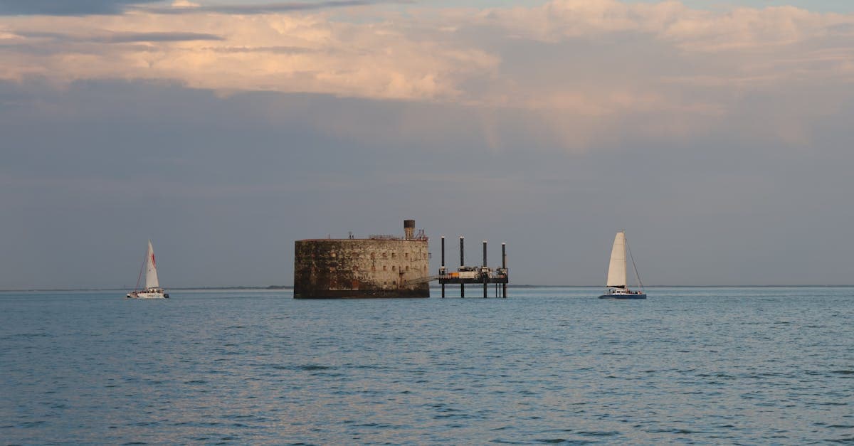 Voiliers longeant un fort historique sous ciel nuageux, choisir la meilleure assurance annulation voyage en 2026