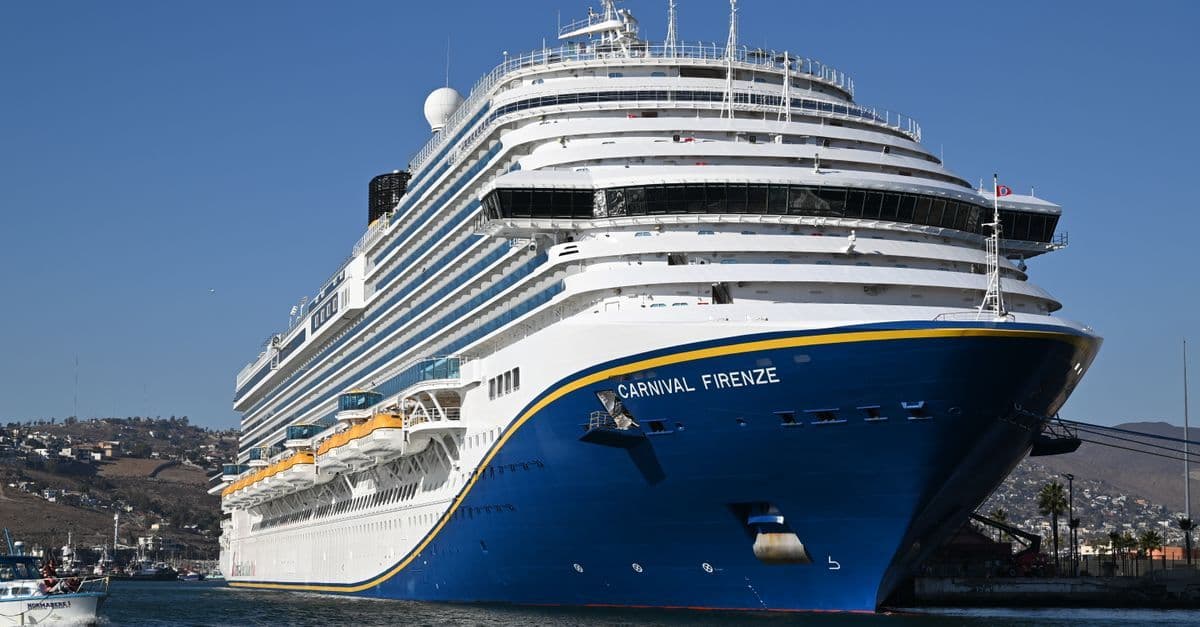 Large cruise ship docked at port under blue skies, perfect for reviewing Carnival Adventure deck plans before boarding.