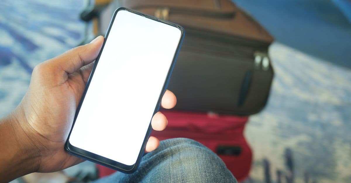 Traveler using smartphone at airport, staying connected with an eSIM while exploring Brazil safely.