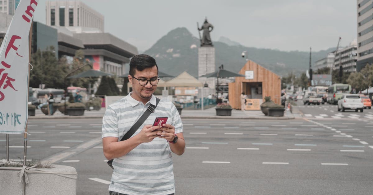 Mężczyzna w koszuli w paski używa smartfona na ulicy — kiedy aktywować kartę eSIM przed wylotem do Japonii