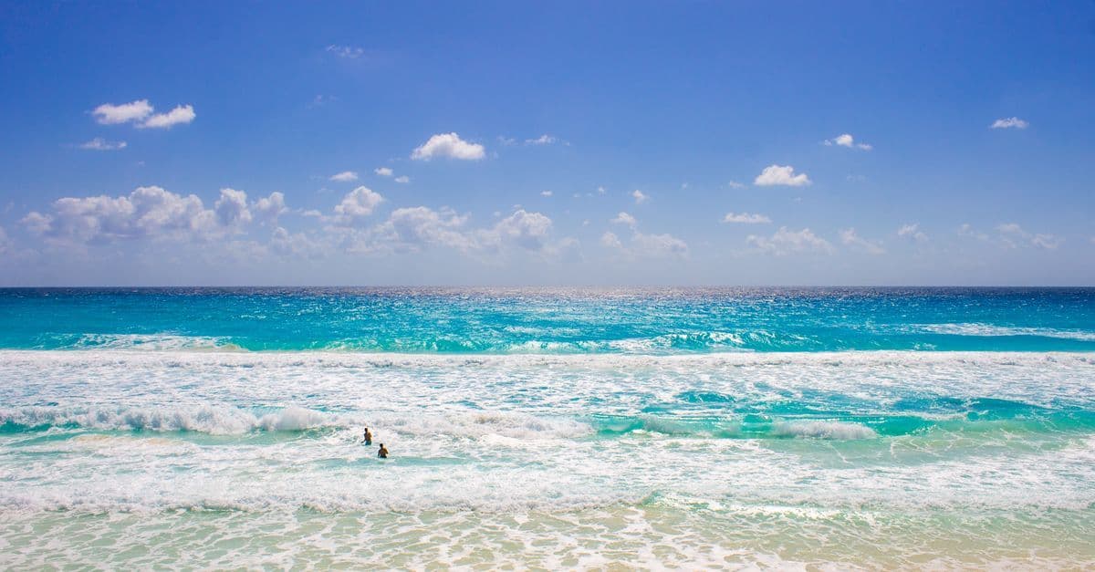 Uncrowded Cancún beach with clear blue water and sunshine, perfect for avoiding spring break crowds.
