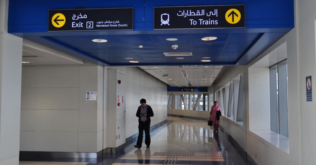 Heller Gang am Flughafen Dubai mit gut sichtbaren Schildern für Ausgang und Bahnsteigzugang.