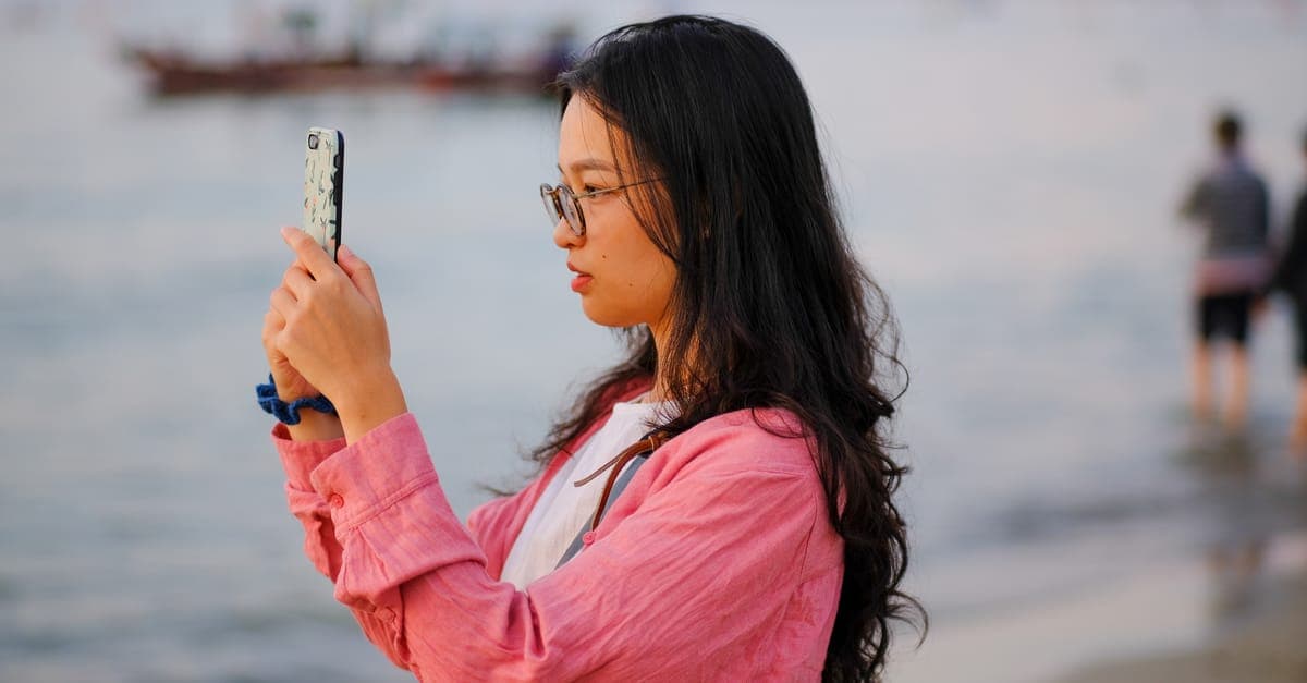 Portrait of a woman capturing beach moments on a smartphone in Hue, Vietnam.