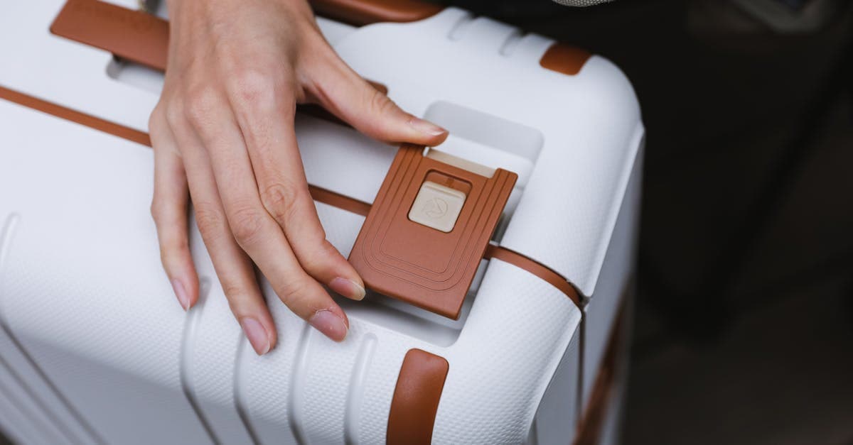Hand using a fingerprint scanner to unlock a white carry on suitcase for secure travel