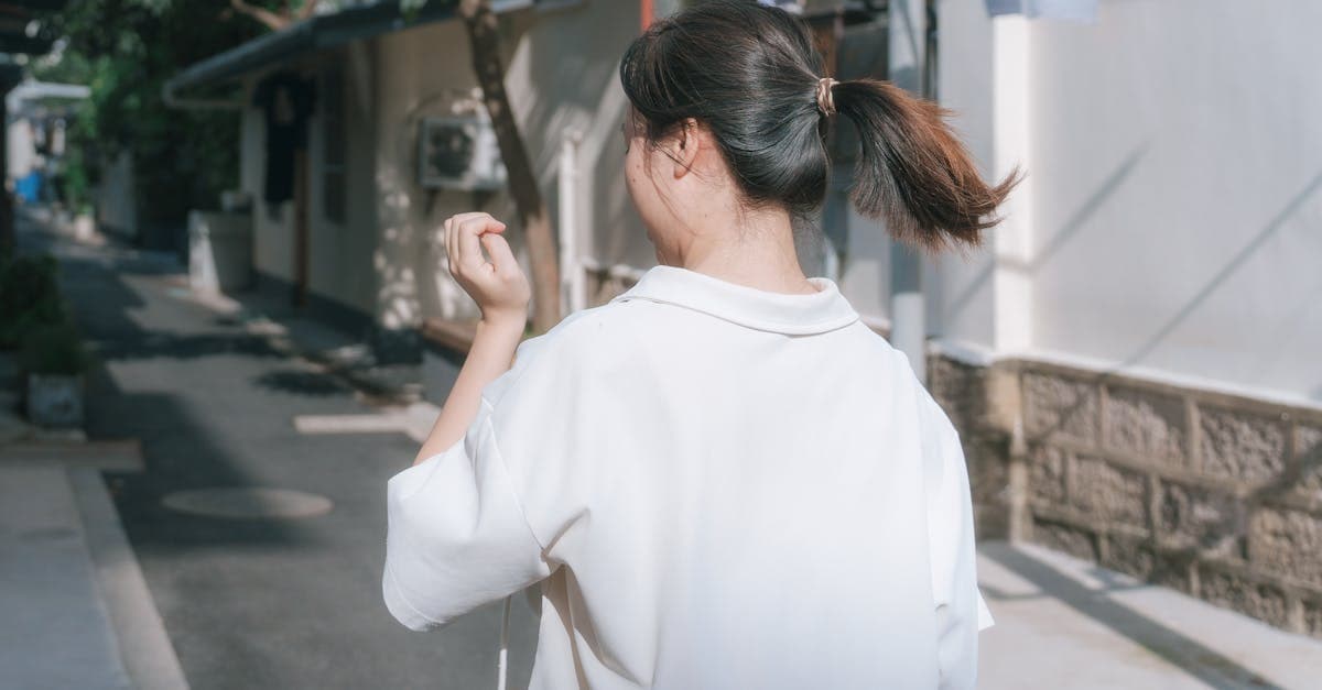 白いブラウスを着た女性が夏の日差し溢れる路地を歩く、2026年一人旅おすすめ先を探す旅人のイメージ