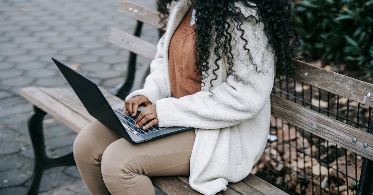 Koncentreret kvinde i varm jakke vælger bærbar wifi mens hun arbejder i byparken