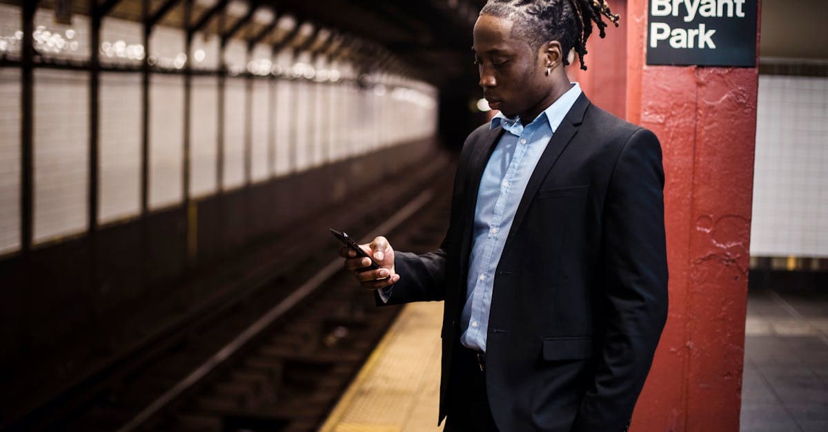 Businessman texting on a cellphone at a Manhattan subway station comparing mobile network coverage