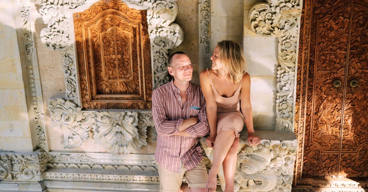Couple relaxing by an ornate Balinese temple wall, enjoying connectivity while exploring Bali