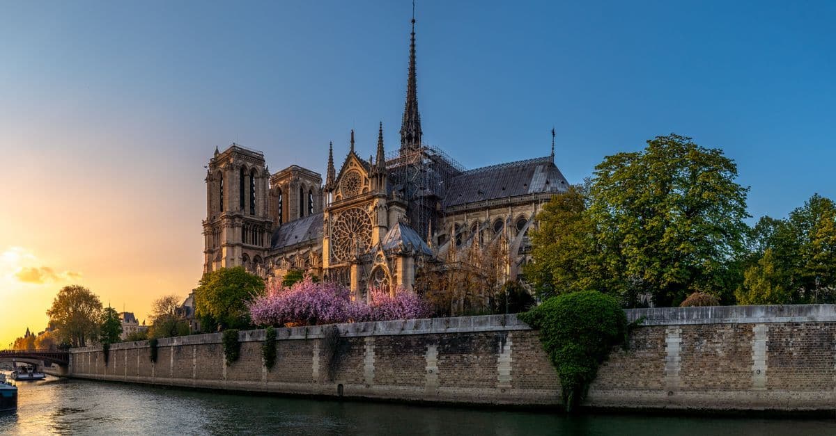 La cattedrale di Notre-Dame di Parigi riaperta, avvolta nella luce calda del tramonto con il fiume sullo sfondo