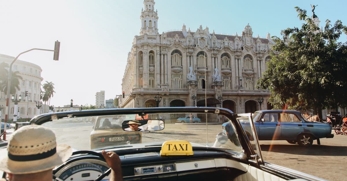 Taxi cabriolet classique devant l'architecture coloniale de La Havane pour vos cheap trips to cuba.