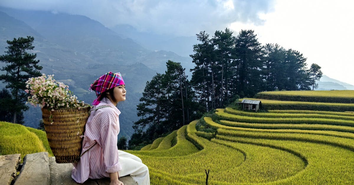 Hmong woman with flowers beside stunning Yên Bái rice terraces, Vietnam.