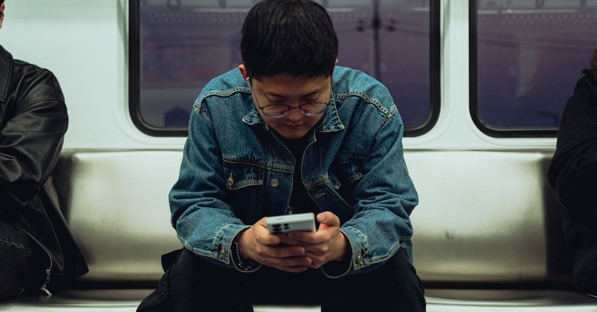 地下鉄の車内でスマートフォンに集中する若い男性、韓国eSIMの購入タイミングを確認中