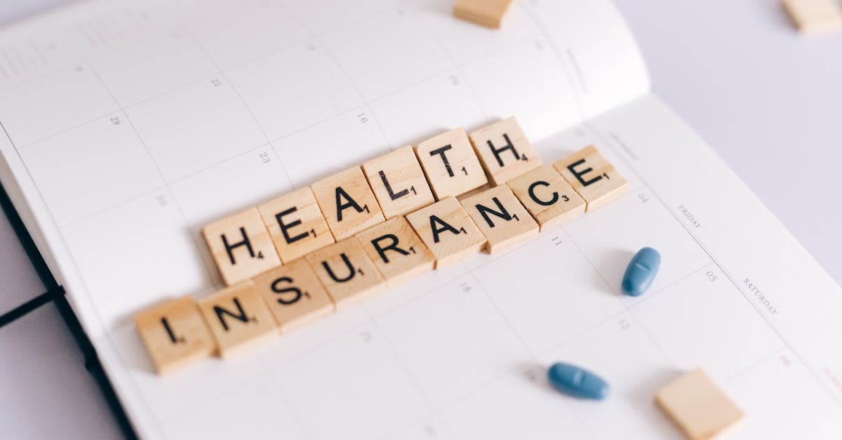 Scrabble tiles spelling health insurance on a planner with medication pills, covering pre-existing conditions for US travel