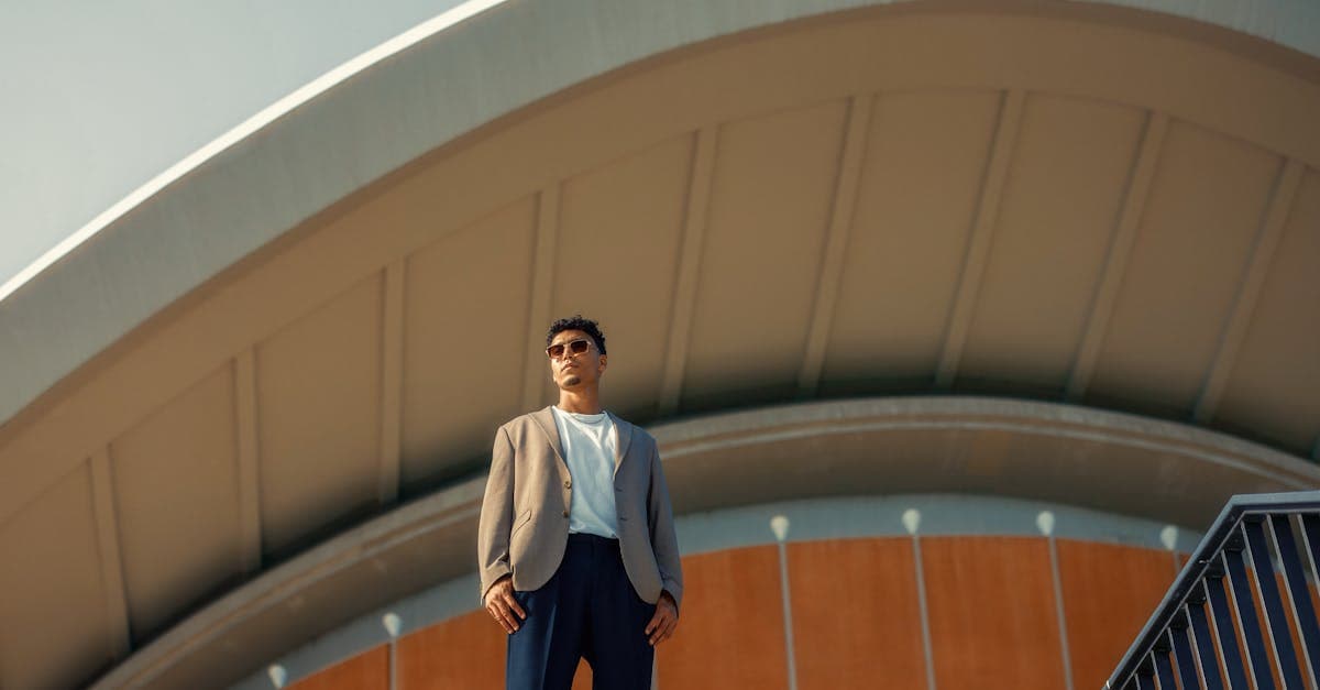 Man in fashionable attire standing in front of the iconic Berlin architecture under bright daylight.
