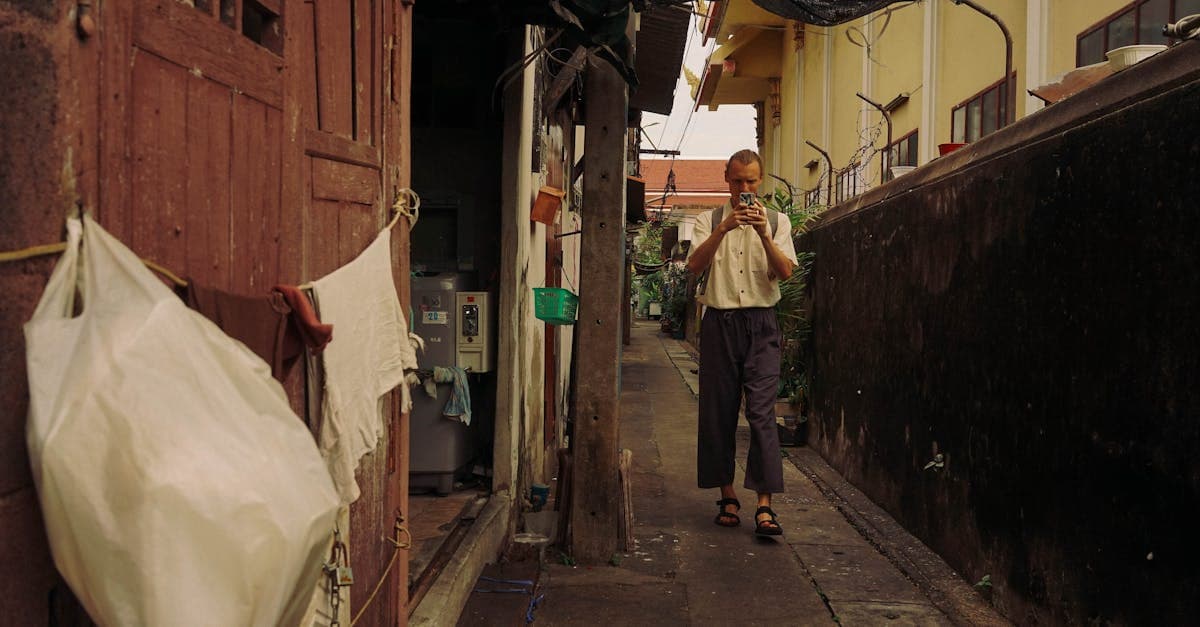Mann navigiert mit dem Smartphone durch eine enge Gasse in Bangkok auf der Suche nach Streetfood