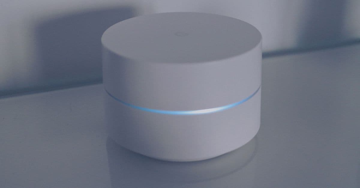 Router domestico con luce blu su superficie specchiata, simbolo di internet casa a 10 euro al mese.