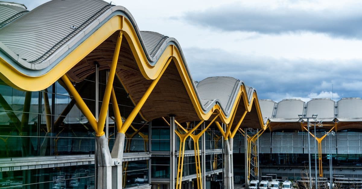 Terminal aeroportuale moderno con tetto ondulato caratteristico e vivaci supporti gialli, architettura innovativa.
