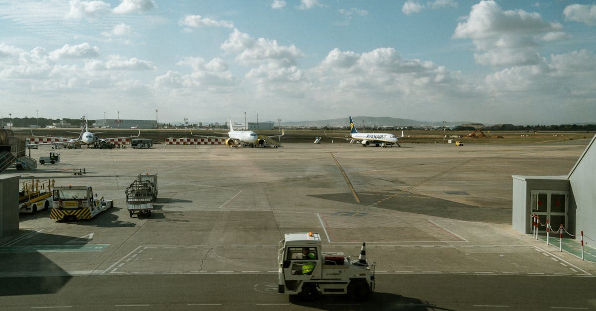 Översikt över Alicante airports flygplatta med flera flygplan och markfordon under molnig himmel.